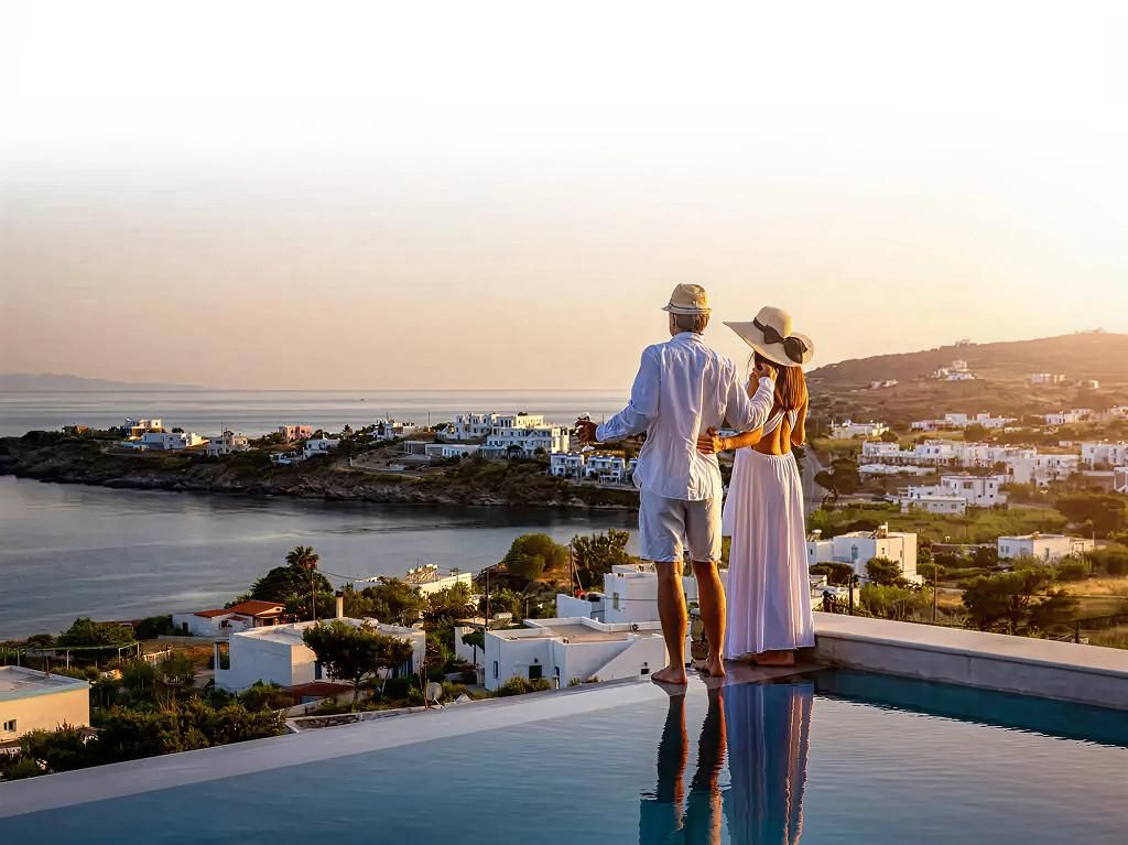 Couple admirant le coucher de soleil sur un village côtier méditerranéen au bord de la piscine à débordement