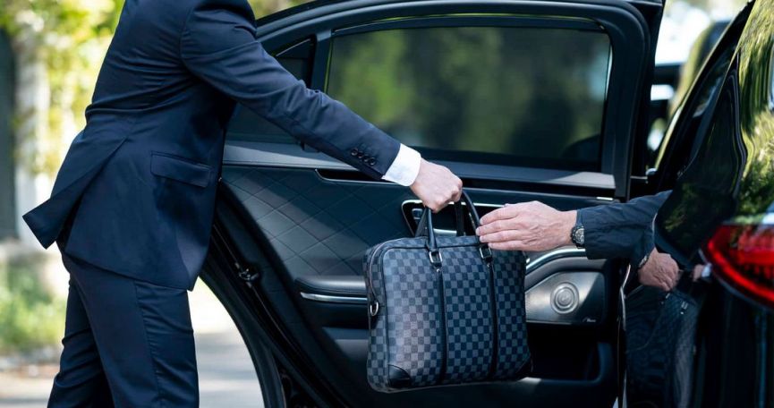 Chauffeur consegna una valigetta a un cliente accanto all’auto