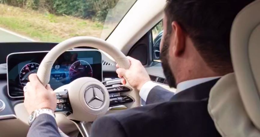 Chauffeur alla guida di una Mercedes su una strada panoramica